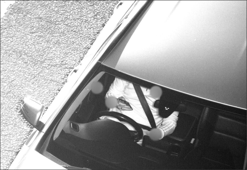 Car driver using mobile phone behind the wheel